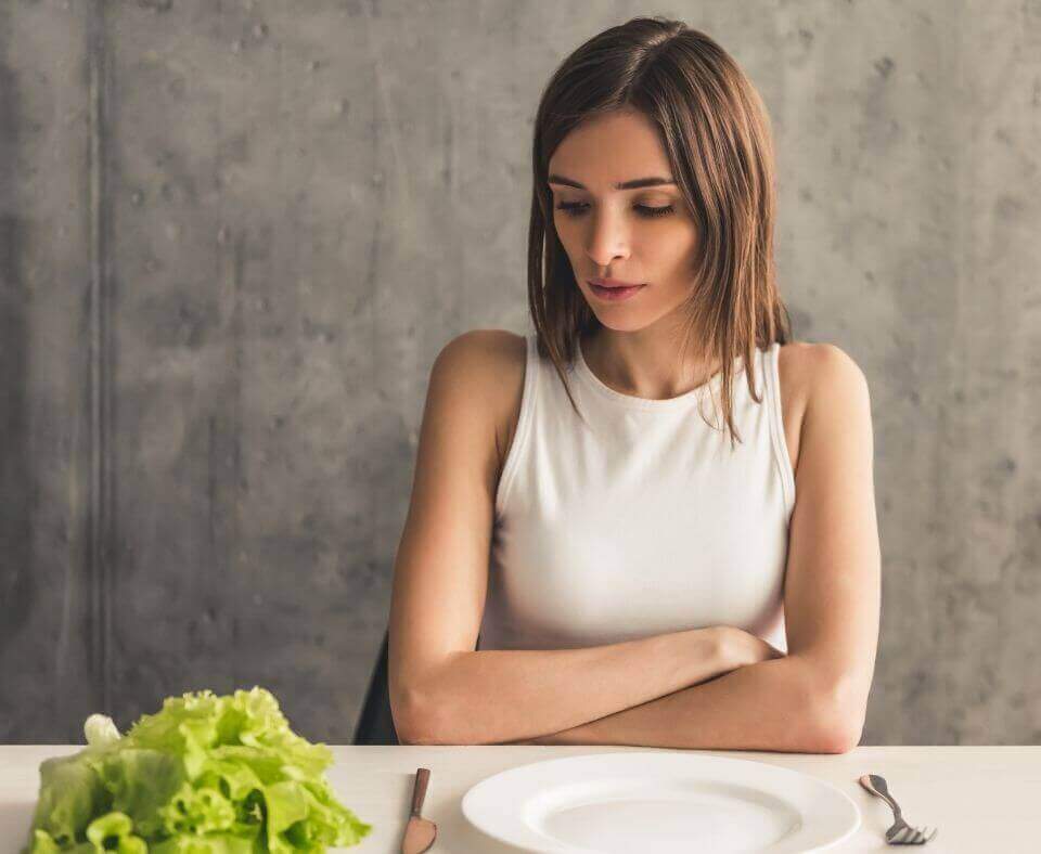 Disordered eating. Girl is sitting in front of an empty plate 